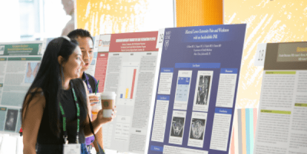 A photo of two people discussing a poster at a conference.